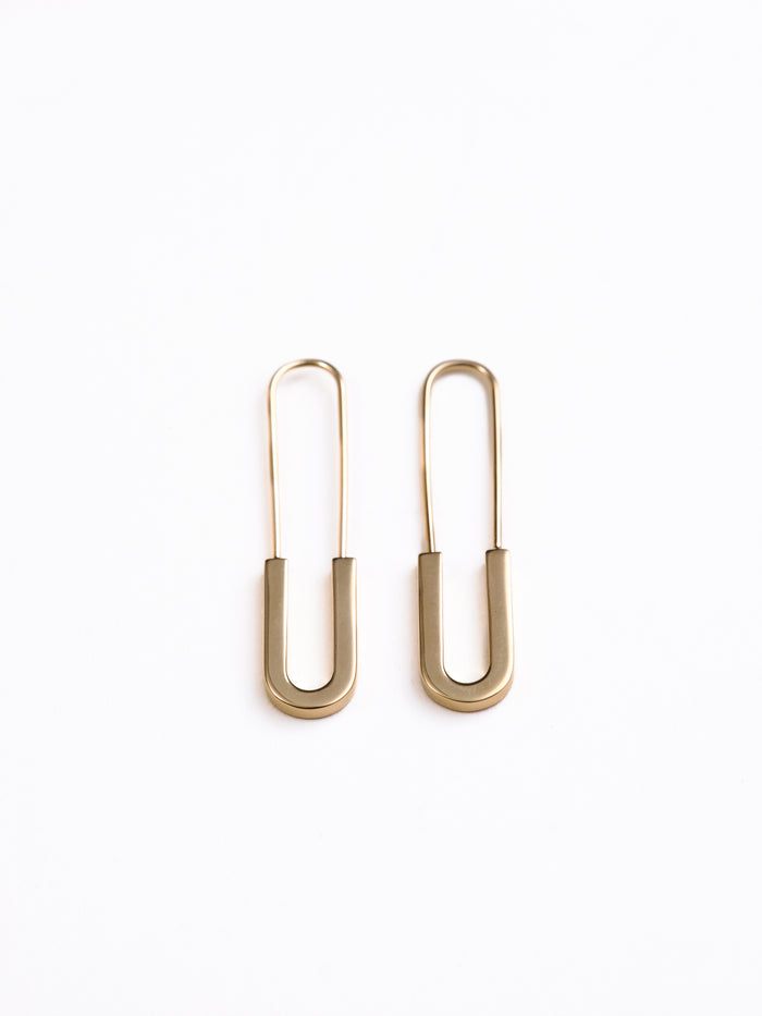 Gold safety pin earrings on a white background